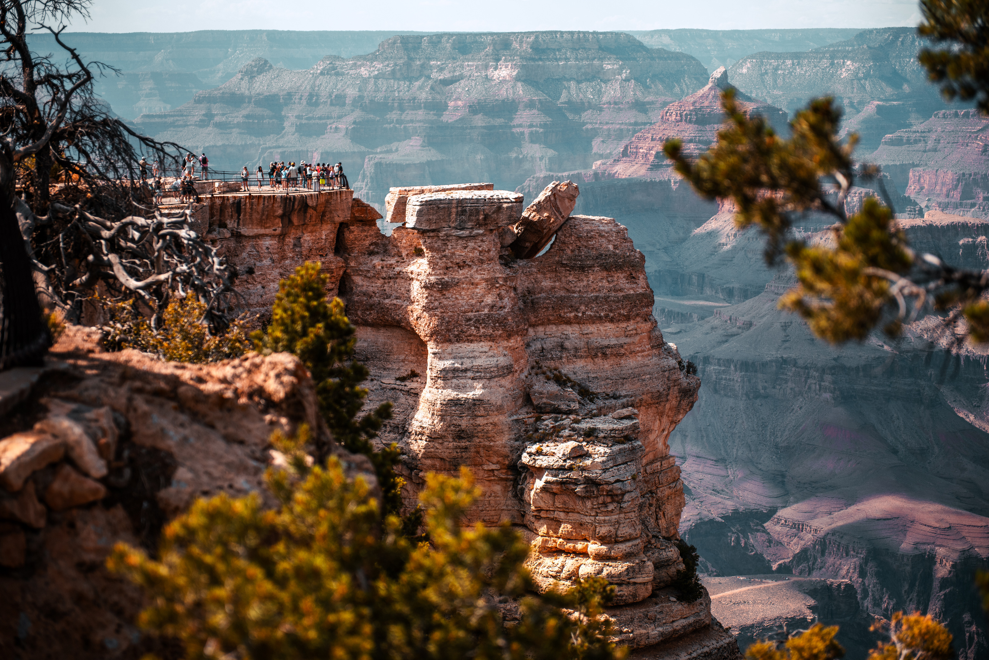 Distant visitors on a canyon overlook platform with dramatic rock spires